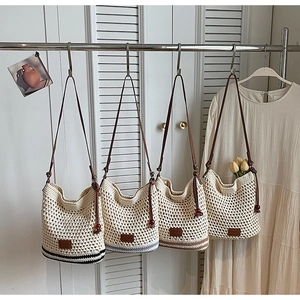 Detail of woven tote bags with leather straps in black, blue, and brown stripes