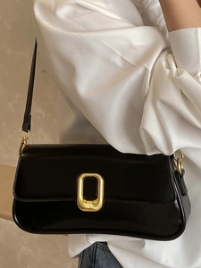 Minimalist black baguette shoulder bag with a large golden textured metal buckle