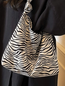 Chic zebra print canvas shoulder bag with unique knotted strap and half-moon silhouette