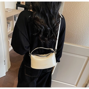 Rear view of model wearing a creamy white semi-moon crossbody bag with gold hardware