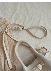 Detail of off-white canvas bag with gold hardware, adjustable strap and padded handles