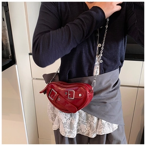 Détail du sac à main rouge en forme de cœur avec boucles argentées et bandoulière