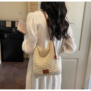 Detail of cream woven tote bag featuring brown leather straps and summer mesh texture