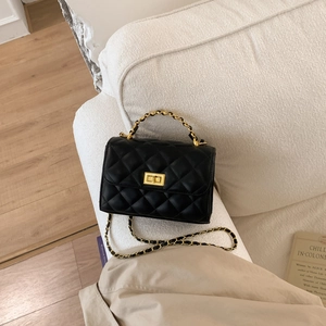 Detail der klassischen schwarzen Stepptasche mit goldenem Drehverschluss und Kettenriemen