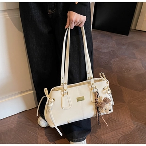 Detailed view of white tote bag with golden metal plate and cute brown bear keychain