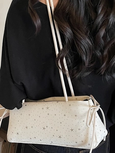 White shoulder bag with star print and side bow detail shown on a female model
