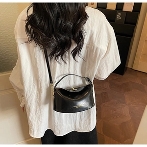Detail of elegant black semi-circle leather bag with gold buckle on white shirt model