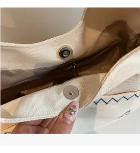 Detail of canvas bag showing magnetic closure, inner zipper pocket and embroidery