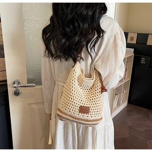 Detail of beige crochet tote bag with wooden beads and brown strap on shoulder