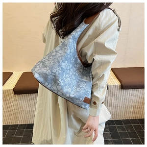 Blue and white floral tote bag with brown leather straps shown worn by a model