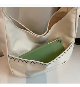 Detail view of canvas bucket bag with blue zigzag stitching and an iPad in outer pocket