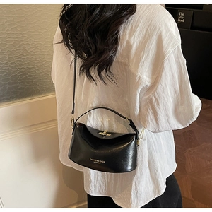 Detail of a black crescent crossbody bag with golden rotary lock and shoulder strap