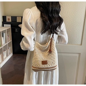 Close-up of beige crochet shoulder bag featuring brown striped base and leather logo