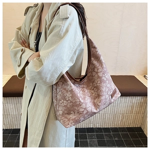Close-up of the vintage floral hobo bag with brown leather strap on model's shoulder