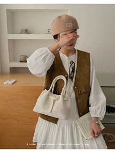 Detail of cream plaid bucket bag featuring leather trim and canvas texture on a model
