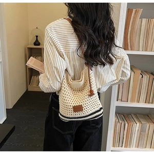 Detail of hand-woven off-white crochet tote with brown leather strap and wood bead accent