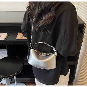 Detail showing the silver half-moon crossbody bag with metallic finish and top handle