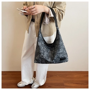 Detail of grey floral hobo bag showing the retro print and black leather shoulder strap