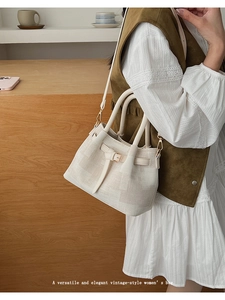 Detail of beige textured handbag featuring gold hardware and a vintage French style strap