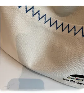 Detail of canvas bag fabric with blue wave embroidery and Docile Girl text