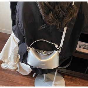 Silver metallic crossbody bag with gold lock shown on model in modern setting