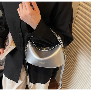 Close-up of a silver metallic hobo shoulder bag worn by a model in black outfit