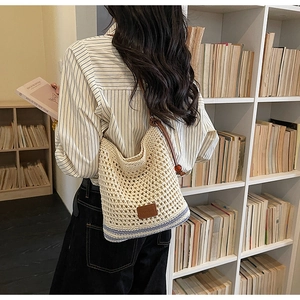 Close-up of woven straw tote bag featuring blue stripes and brown leather brand patch