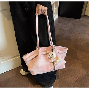 Detail of pink plaid tote bag featuring a leather horse charm and metallic lock