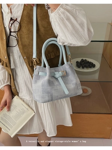 Detail of grey patterned handbag with light blue leather straps and gold metal buckles