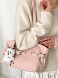 Sac fourre-tout en cuir rose avec œillets et peluche sur pull en maille blanc