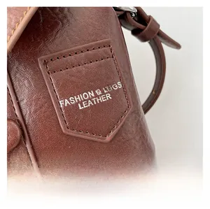 Close-up of dark brown leather handbag with shield logo and silver hardware details