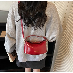 Close-up of a red glossy patent leather handbag with a stylish semicircular structured design