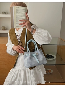 Chic light blue bucket bag with leather handles shown in a retro lifestyle setting