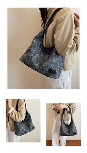 Detail of dark grey floral tote bag with textured canvas and wide black shoulder strap