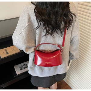 Detail of red glossy leather crossbody bag with gold fashion lettering and metal buckle