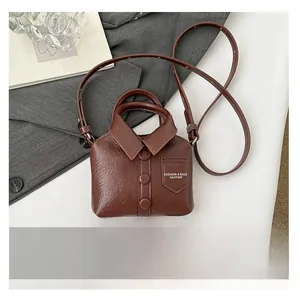 Detail view of mini brown shirt-style crossbody bag compared with a smartphone