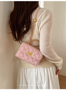 Rückansicht einer rosa gesteppten Kettentasche mit goldenem Drehverschluss am Outfit