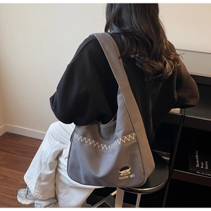 Detail of grey canvas hobo bag with cute girl embroidery and comfortable wide strap