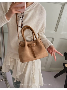 Detail of vintage-style textured tote bag with leather straps and metal buckle accent
