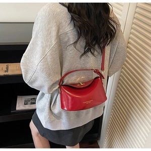 Detail view of red glossy leather shoulder bag with gold twist lock and brand logo