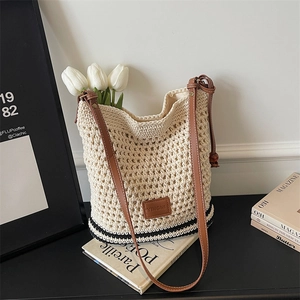 Detail of woven tote bag featuring cream cotton texture and brown leather branding strap