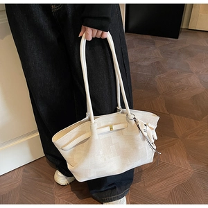 Detail of a beige tote bag featuring a cute white rabbit plush charm and slim handles