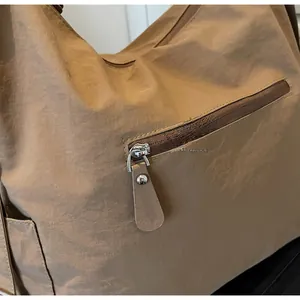 Detail of smooth metal zipper on khaki nylon tote bag with crinkle texture finish