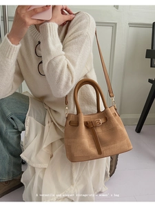 Detailed close-up of a camel woven handbag with leather straps in a home setting