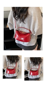 Detail of red glossy leather handbag featuring gold metal clasp and top handle