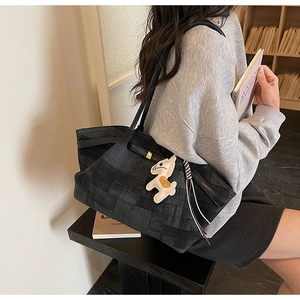 Detailed view of spacious black jacquard tote bag with stylish horse charm in a library setting