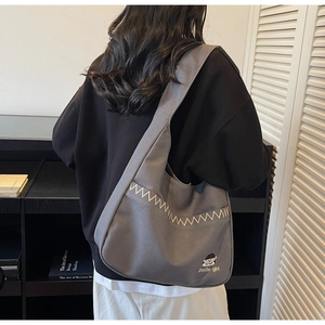 Detail of grey canvas crossbody bag with zigzag embroidery and cartoon girl patch