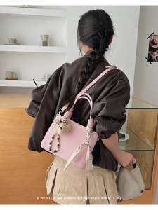 Detail of pink lychee textured handbag with bear pendant and scarf accessory