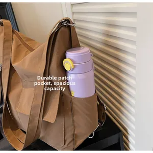 Detail of a brown large capacity shoulder bag showing a side pocket holding a water bottle