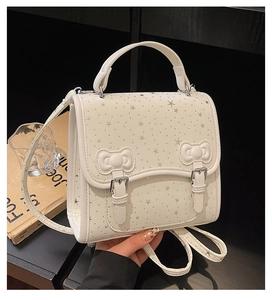 Close-up of white leather handbag with silver star prints and 3D bow details